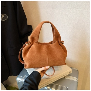 Detailed view of the brown suede crossbody bag with gold metal rings and pleat details