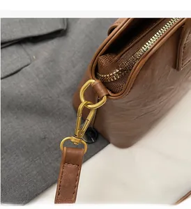 Close-up of golden zipper hardware and textured brown leather on a shoulder bag