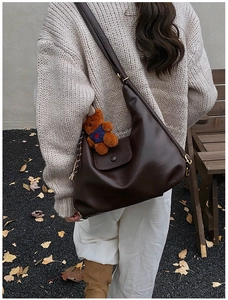 Detail of a dark brown PU leather tote bag with cute bear charm and golden buckle