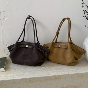 Detail of suede tote bags featuring slim shoulder straps and gold metal buckle closures