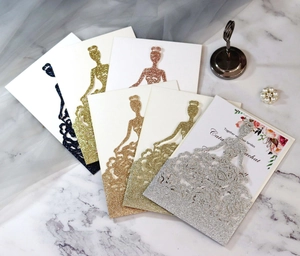 Macro view showing laser-cut glitter wedding invitations with elegant bride silhouette