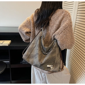 Detail of vintage grey tote bag with silver chains and heart charm worn by a model