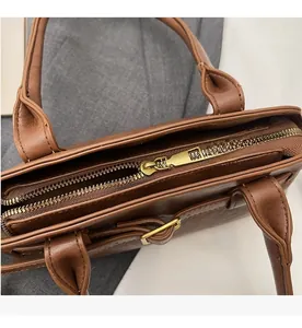 Close-up of smooth golden metal zipper and texture on dark brown leather handbag