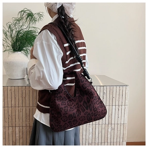 Detail view of burgundy leopard print shoulder bag with knotted strap on model in minimalist interior
