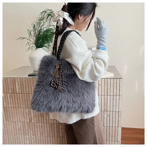 Detail of grey fluffy faux fur shoulder bag with black braided strap and metal charms