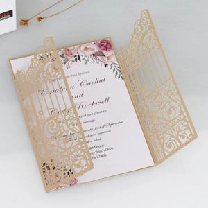 Detail of laser-cut gold wedding invitation with floral insert and intricate pattern