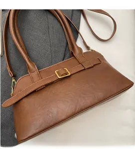 Detail of a brown leather shoulder bag with gold metal buckle and dual top handles