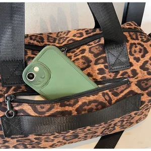 Détail de la poche zippée latérale du sac léopard contenant un smartphone