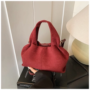 Macro detail of wine red suede handbag showing natural folds and matte texture