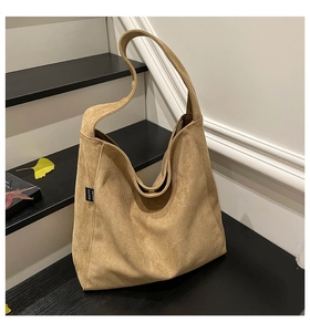 Close-up of camel suede hobo tote bag texture on minimalist indoor stairs