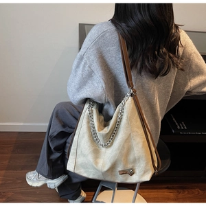 Macro shot of retro beige hobo bag with silver chain and brown leather strap detail