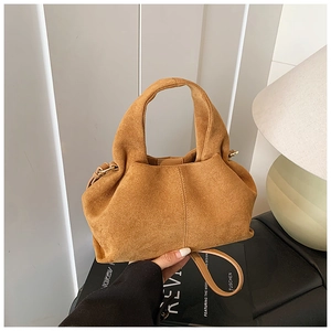 Detailed view of caramel suede handbag showing pleated half-moon shape and gold hardware