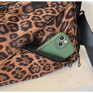 Détail d'une poche latérale zippée sur un sac cabas léopard avec un smartphone vert