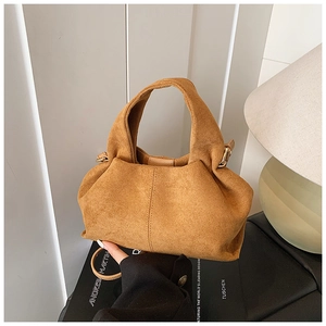 Detailed view of brown suede bucket bag with pleats and gold hardware accents