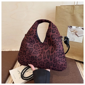 Detail of leopard print tote bag with integrated handle and black leather shoulder strap