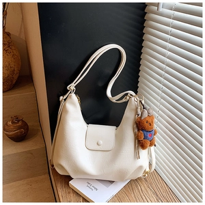 Detail of off-white PU leather shoulder bag with a cute brown teddy bear keychain