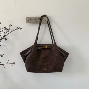 Detailed view of dark brown suede tote bag featuring PAN TOR gold lettering and drawstrings