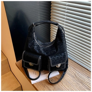 Macro detail of black leopard print shoulder bag with white stitching and metal buckles