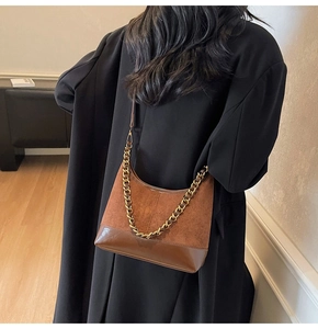 Brown dumpling bag with vintage gold chain detail and mixed texture material close-up