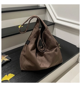Detailed view of dark brown suede tote bag on stairs with autumn leaves