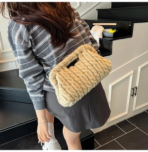 Close-up of beige chunky knit cloud bag with golden chain strap on a model