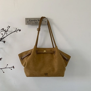Close-up of brown suede tote bag with golden PAN TOR logo and decorative leather strap