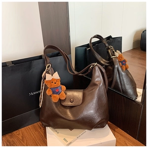 Detail of coffee brown moon-shaped tote bag with glossy PU leather and bear charm