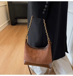 Detail of hobo bag with suede and leather patchwork featuring golden metal chain strap