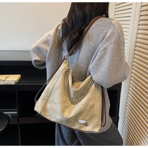 Detail view of beige vintage tote bag with metal chain strap and matte texture on model