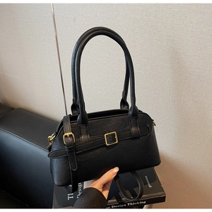 Close-up of black minimalist tote bag featuring lychee texture and gold buckle detail
