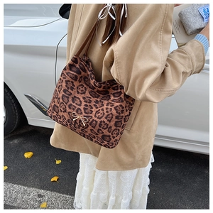 Dettaglio della borsa tote leopardata con fiocco in metallo dorato e manici in cuoio