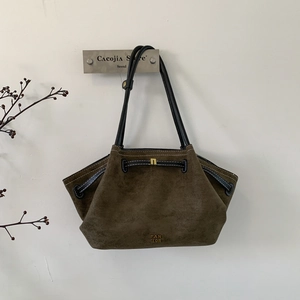 Macro detail of brown suede tote bag with pleated texture and golden brand engraving