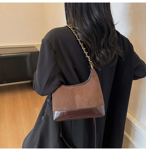 Retro patchwork underarm bag with suede and glossy leather details on a model