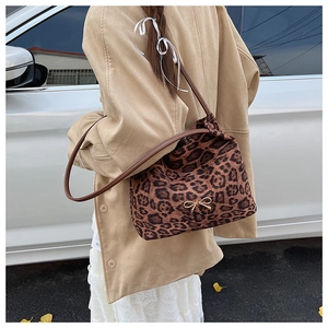 Detail of leopard print suede shoulder bag with gold bow clasp and brown leather strap