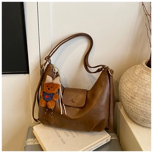 Close-up of caramel hobo bag with vintage gold hardware and a cute teddy bear charm