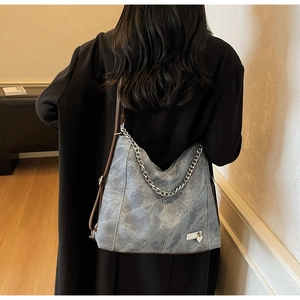 Detail of gray distressed leather tote showing dual silver chain and brown shoulder straps