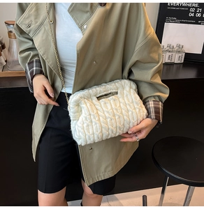 Close-up of white chunky knit crossbody bag with cable pattern and gold chain strap