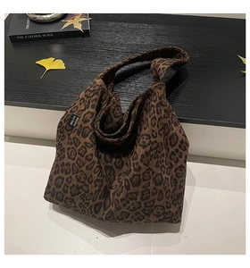 Close-up of leopard print canvas tote bag with brand label and autumn leaves