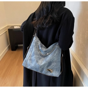 Detail of blue washed denim texture bag with silver chain and heart lock pendant