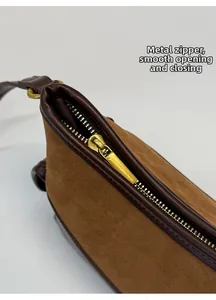 Details von goldenem Metallreißverschluss und Lederbesatz an brauner Wildledertasche