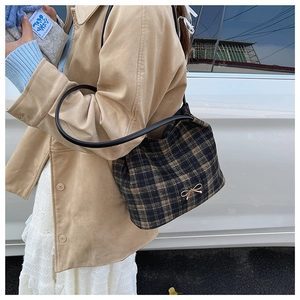 Detail of vintage plaid bucket bag with a golden bow buckle and black leather strap