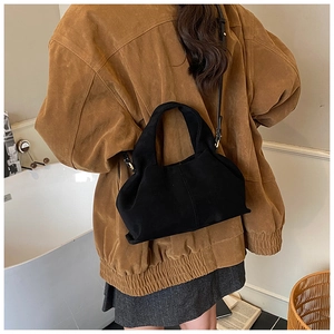 Close-up of a black suede crossbody bag showing its soft texture and metal buckle detail