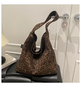 Close-up of a large leopard print tote bag hanging on a white door with a minimalist background