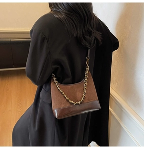 Close-up of brown suede hobo bag with contrast leather bottom and metal chain strap