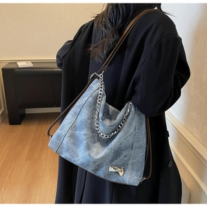 Close-up of vintage blue denim tote with silver chain and heart pendant detail