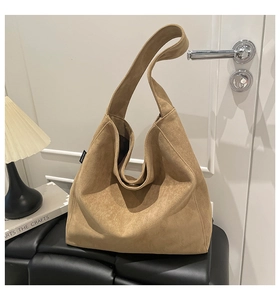 Detail of Malivy suede hobo bag on a leather bench in a cozy home interior setting