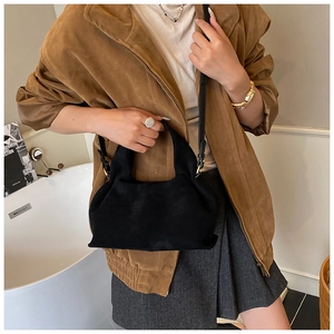 Detail of minimalist black suede hobo bag with adjustable strap in a modern setting