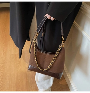 Detail of dark brown suede and leather hobo bag with gold chain and crossbody strap