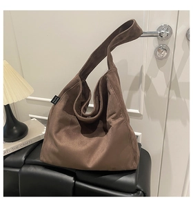 Detail view of large dark brown suede tote bag featuring a black Malivi logo side label