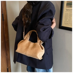 Detail of vintage camel suede handbag with pleated texture and adjustable shoulder strap